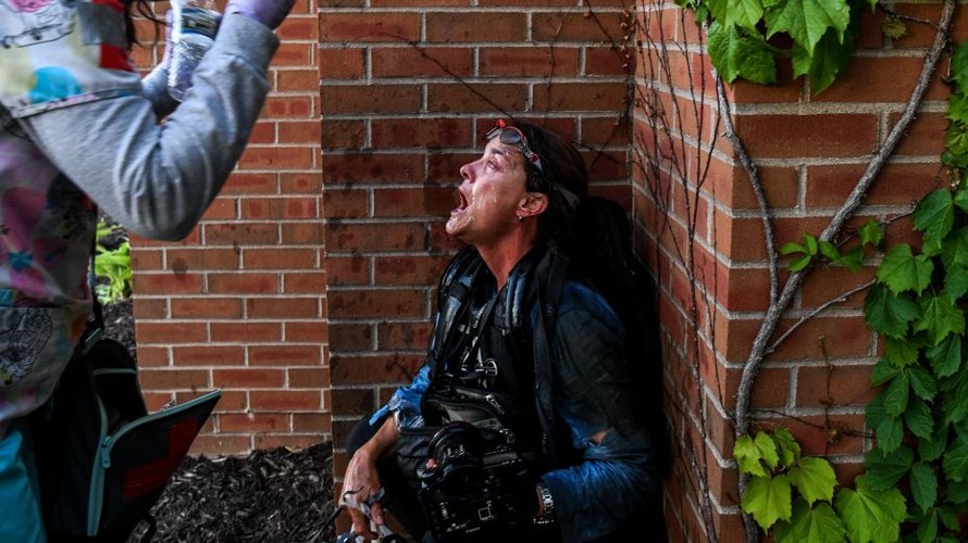 Một nhà báo được phun nước lên mặt sau khi dính hơi cay tại Minneapolis. Ảnh: AFP