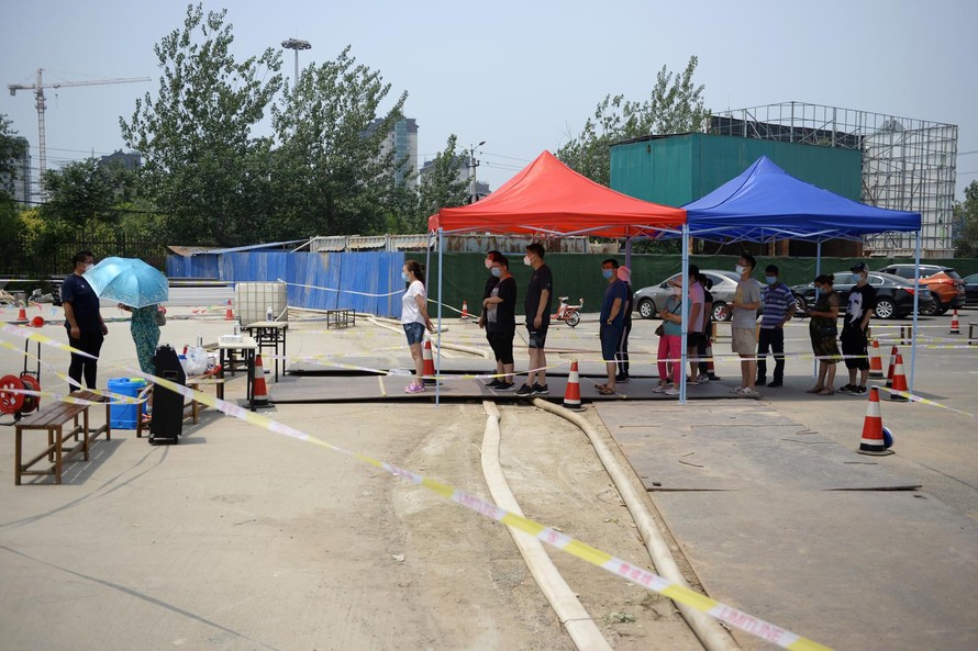 Một hàng người đeo khẩu trang đang đứng chờ xét nghiệm tại Bắc Kinh. Ảnh: REUTERS