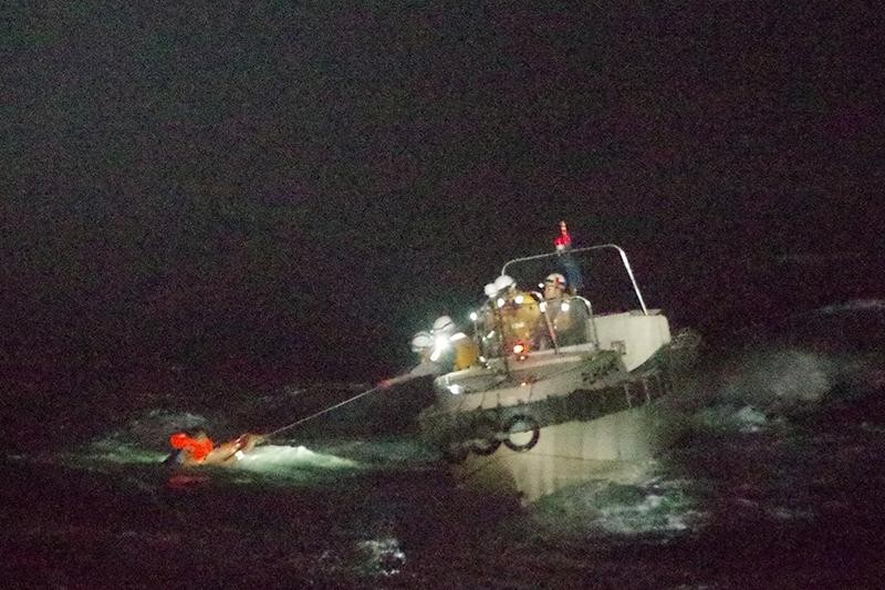 Lực lượng cứu hộ kéo một thuyền viên lên tàu. Ảnh: Reuters
