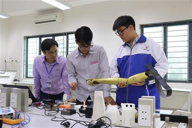 Hai nam sinh Phạm Đức Linh và Nguyễn Văn An cùng nhau nghiên cứu sản phẩm Cánh tay robot cho người khuyết tật liệt cơ tay toàn phần. Ảnh: TTXVN