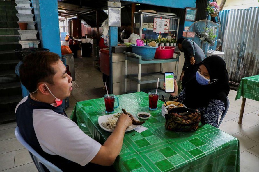 Thực khách tại thủ đô Kuala Lumpur của Malaysia xuất trình chứng nhận tiêm chủng để được dùng bữa trong nhà hàng. Ảnh: Reuters