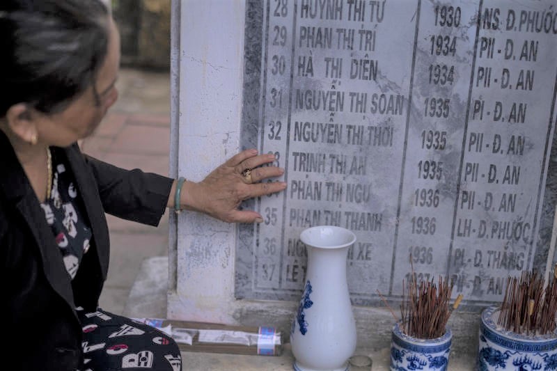 Bà Nguyễn Thị Thanh bên tấm bia khắc tên những nạn nhân của vụ thảm sát năm 1968. Ảnh: NY Times