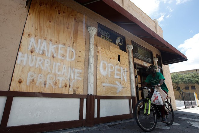 Người dân "trang trí" các tấm gỗ dùng để gia cố cửa bằng những thông điệp hài hước: "Tiệc đón bão khỏa thân mở cửa lối này". Ảnh: Reuters.