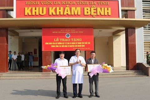 Bác sĩ Nguyễn Viết Đồng, Giám đốc Bệnh viện Đa khoa Hà Tĩnh (áo trắng, ở giữa) trao bằng khen cho hai cá nhân hiến máu cứu người