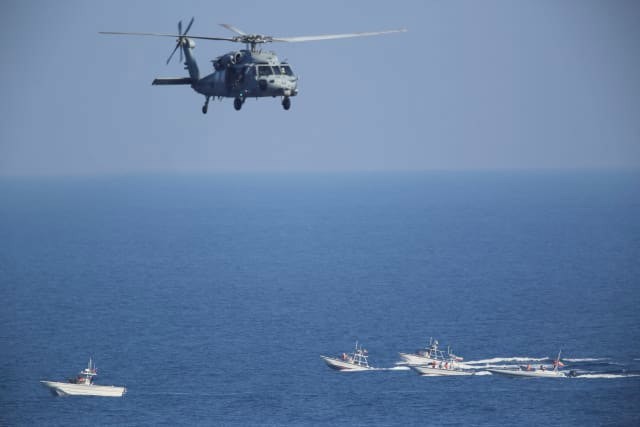 Một trực thăng quân sự MH-60 Seahawk của Mỹ đang bay phía trên đầu các tàu tuần tra của Iran ở gần nơi Lực lượng Vệ binh Cách mạng Iran tập trận hôm 21/12. Ảnh: AP