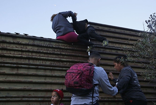 Những người di cư nhau vượt qua bức tường biên giới Mỹ từ Mexico. Ảnh: AP