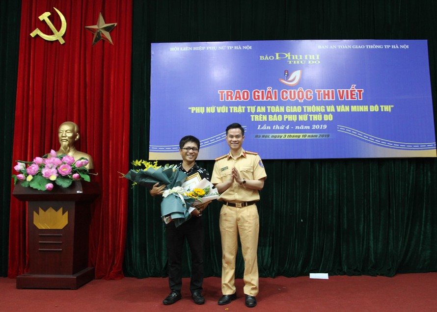 Thiếu tá Đào Việt Long, Phó Trưởng phòng Cảnh sát giao thông, Công an TP Hà Nội tặng hoa chúc mừng tác giả đoạt giải Nhất.