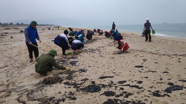 Đoàn viên, thanh niên thu gom cặn dầu trôi dạt vào bờ biển xã Kỳ Lợi, thị xã Kỳ Anh. (Ảnh: Phan Quân/TTXVN)