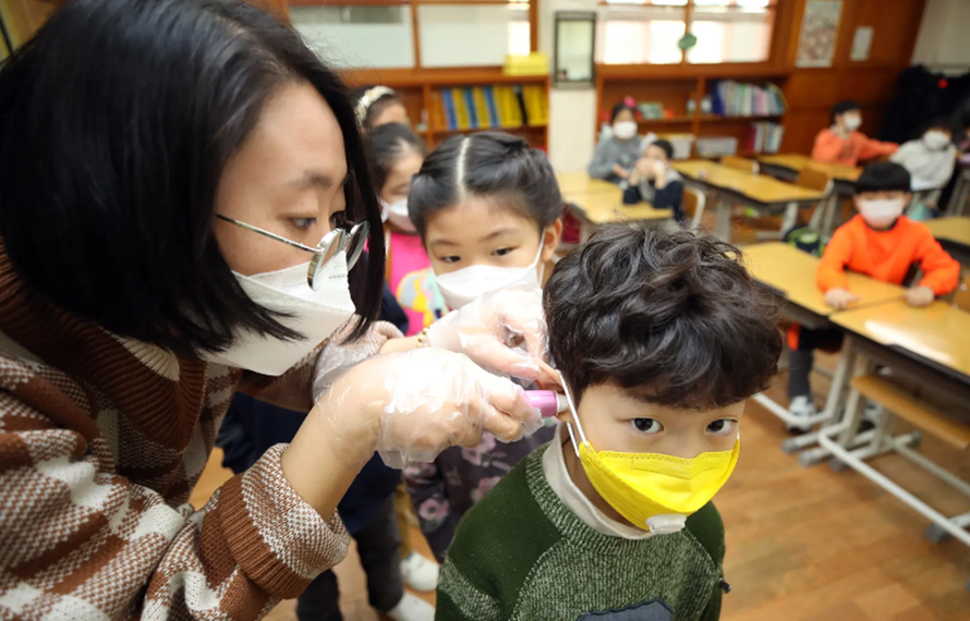 Một giáo viên kiểm tra thân nhiệt của học sinh trong bối cảnh lo ngại về dịch COVID-19 vùng phát khi các trường học trở lại sau kỳ nghỉ Đông ở Hàn Quốc. (Nguồn: Yonhap