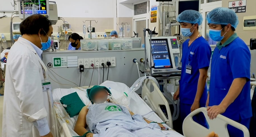 PGS.TS.BS Nguyễn Văn Chi (bên trái) đang thăm khám và hội chẩn tại giường cho một bệnh nhân nặng điều trị tại Khoa Cấp cứu A9.