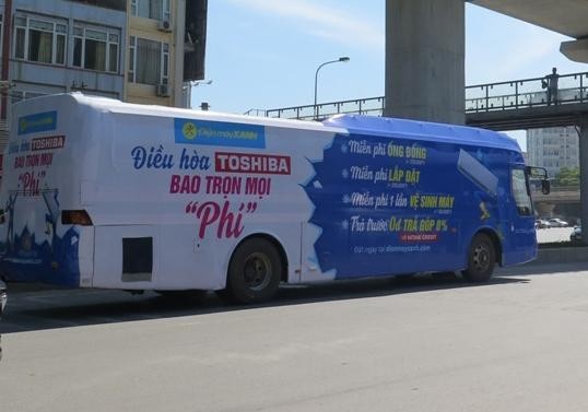  Một xe khách phủ kín đề can quảng cáo lưu thông trên đường phố Hà Nội. Ảnh: Hà Nội Mới.