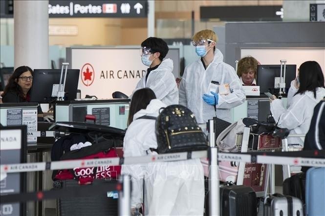 Du khách đeo khẩu trang phòng dịch COVID-19 tại sân bay quốc tế Pearson ở Toronto, Canada ngày 14/4/2020 - Ảnh: THX/TTXVN
