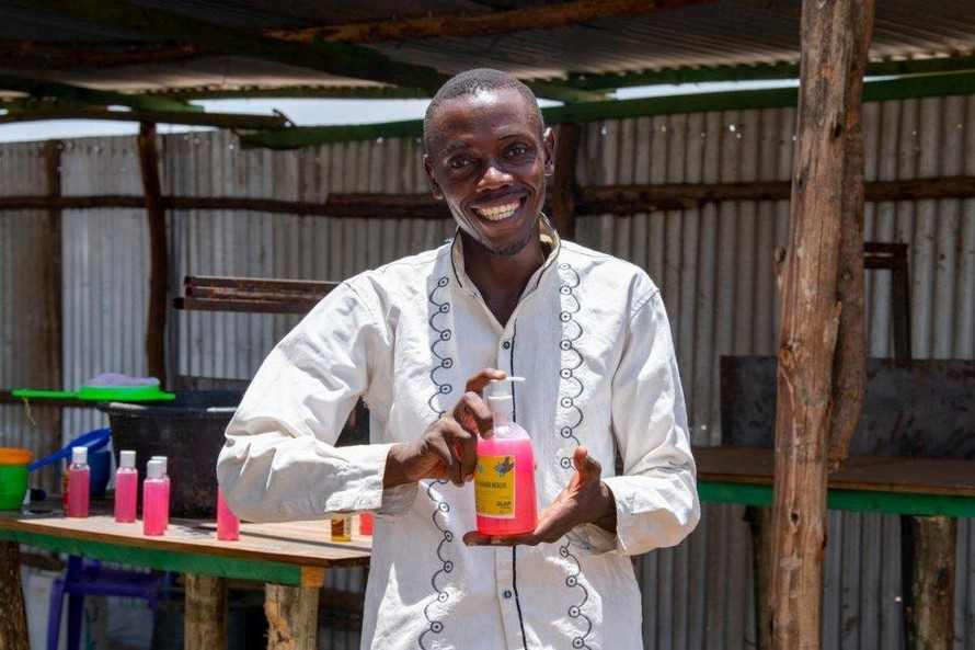 Innocent Havyarimana, một doanh nhân người Burundi, cầm một chai nước rửa tay mới làm, mà anh ta bán cho những người tị nạn, nhân viên cứu trợ và người Kenya ở trại Kakuma, Kenya. © UNHCR / Samuel Otieno