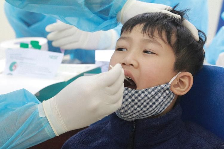 Học sinh trường Tiểu học Xuân Phương (Hà Nội) được nhân viên Trung tâm Y tế quận Nam Từ Liêm lấy dịch phết mũi và họng. Ảnh: Lê Phú.