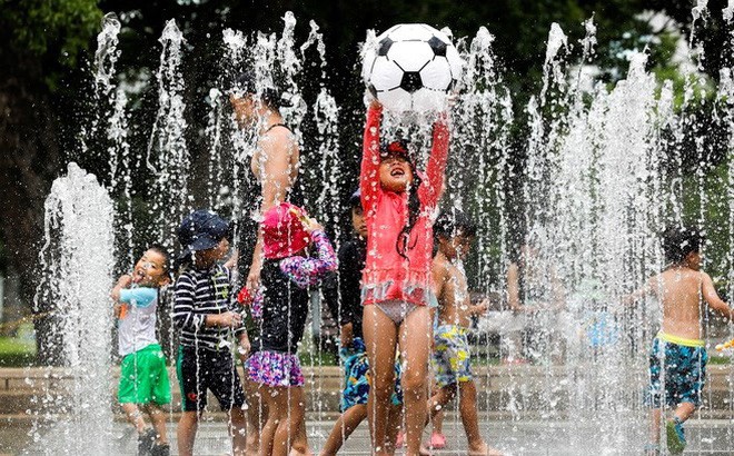 Trẻ em chơi đùa dưới vòi phun nước để tránh nắng nóng tại Tokyo của Nhật Bản ngày 23/7. (Ảnh: EPA/TTXVN)