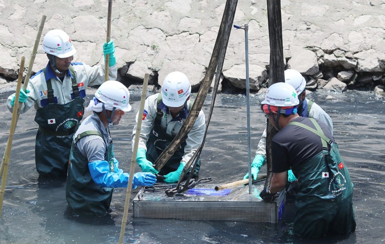 Các kỹ sư và công nhân hạ thiết bị xử lý ô nhiễm xuống sông Tô Lịch sáng 16/5. Ảnh: Võ Hải.