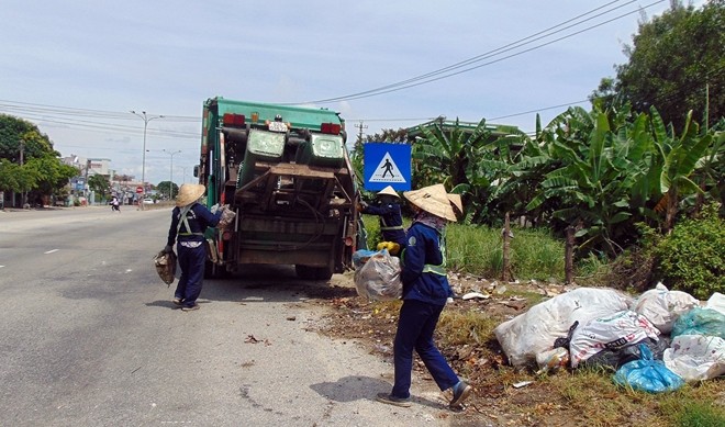 Công nhân vệ sinh môi trường thu gom rác bên tuyến QL1A đoạn qua thị trấn Núi Thành, huyện Núi Thành.