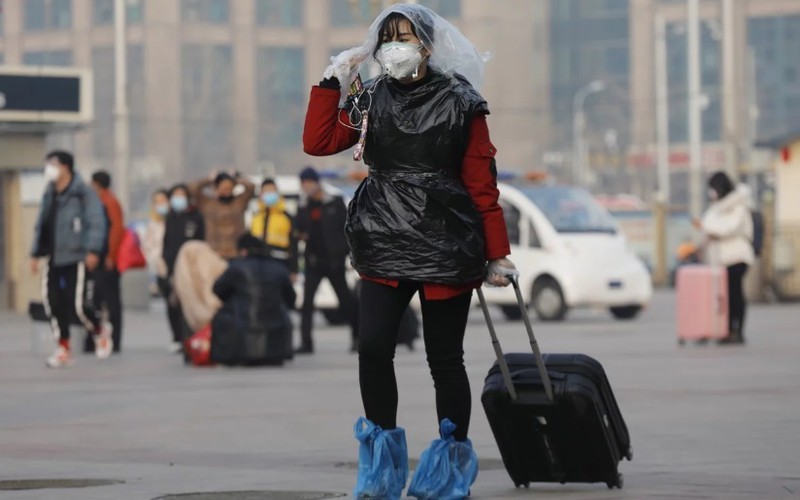 Một nữ hành khách ở ga tàu hỏa Bắc Kinh dùng túi nylon che đầu, chân và thân để phòng virus corona chủng mới Covid-19. - Ảnh: EPA.