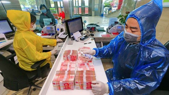 Một nhân viên tẩy uế các đồng bạc đã qua sử dụng tại trụ sở Ngân hàng Toại Ninh (Tứ Xuyên, Trung Quốc) ngày 26/2/2020 