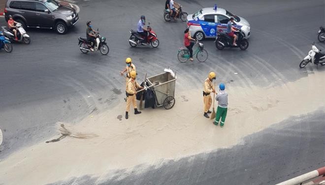 Lực lượng chức năng cùng nhân viên vệ sinh môi trường dọn cát rơi vãi trên đường. - Ảnh: VTC News