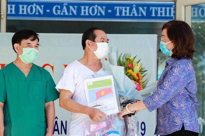 "Bệnh nhân 936" (áo trắng) nhận hoa chúc mừng từ Giám đốc Sở Y tế Ngô Thị Kim Yến. - Ảnh: Vnexpress
