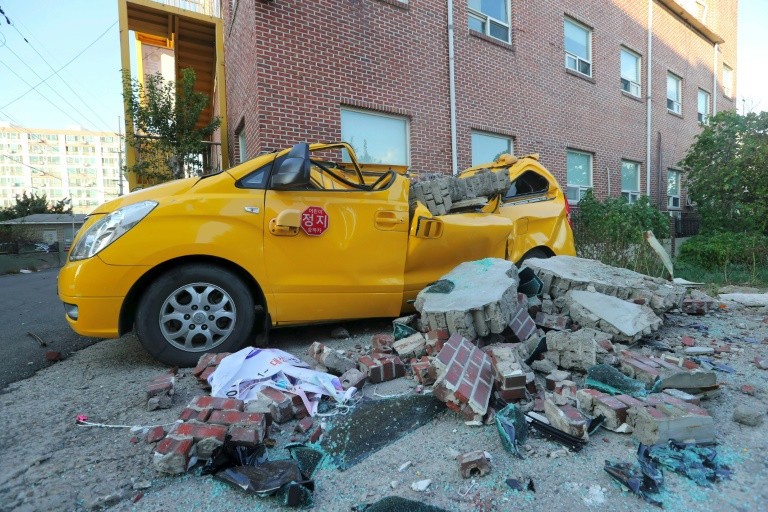 Xe ô tô bị gạch đá phá hủy do động đất. Ảnh: YONHAP