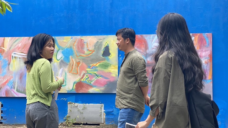 Họa sĩ Bùi Quang Viễn (giữa) đang khoe tranh “Những tình huống mới” với bạn bè của anh.