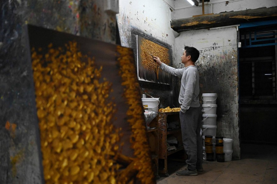 Một hoạ sĩ đang vẽ tranh tại nhà xưởng ở làng Dafen, Trung Quốc.