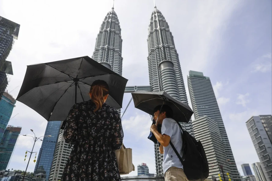 Một cặp đôi đang che ô để tránh nắng tại thủ đô Kuala Lumpur, Malaysia. Ảnh: SCMP. 