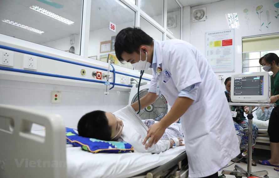 Bác sỹ tại Bệnh viện Xanh Pôn khám cho một bệnh nhi mắc sốt xuất huyết trong tình trạng nặng. Ảnh: TTXVN.