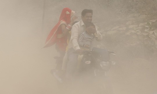 Một gia đình lái xe trong bụi mù dày đặc ở New Delhi