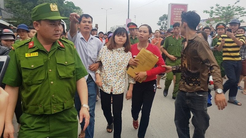 Một nữ thanh niên (áo hoa) được người dân dìu đi sau khi bị công an kiểm tra ở ngôi nhà số 744 đường Quang Trung, phường Đông Vệ, TP Thanh Hóa, nơi truyền đạo của “Hội thánh đức chúa trời”