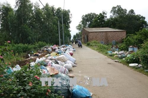Rác ùn ứ nhiều ngày đã tràn ngập đường đi khi người dân chặn xe chở rác. Ảnh: Đinh Hương/TTXVN