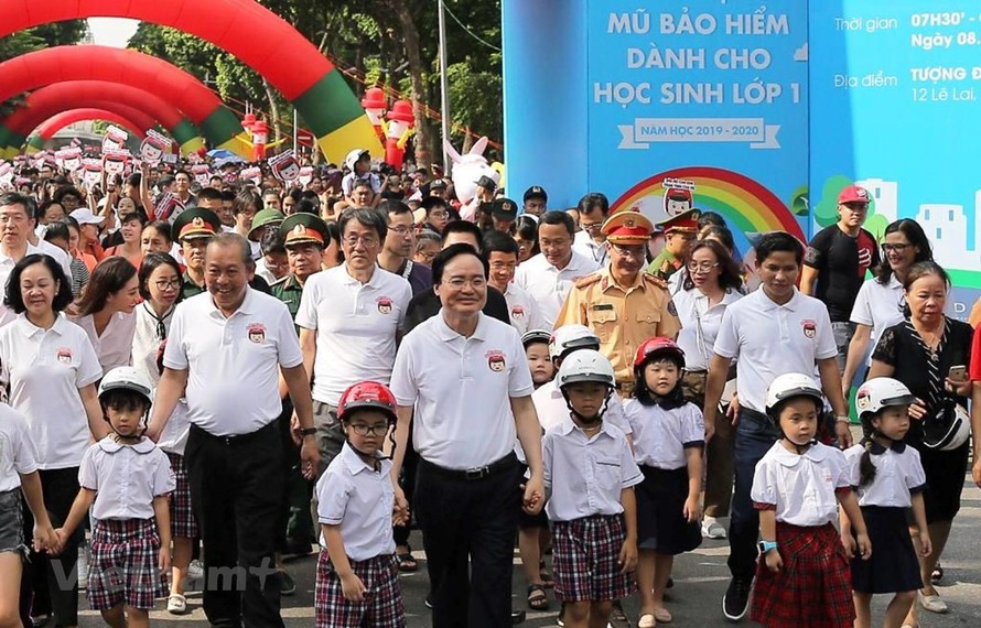 Lãnh đạo Chính phủ và các Bộ, ban ngành đi bộ kêu gọi toàn dân đội mũ bảo hiểm cho trẻ em khi tham giao giao thông. (Ảnh: Việt Hùng/Vietnam+)