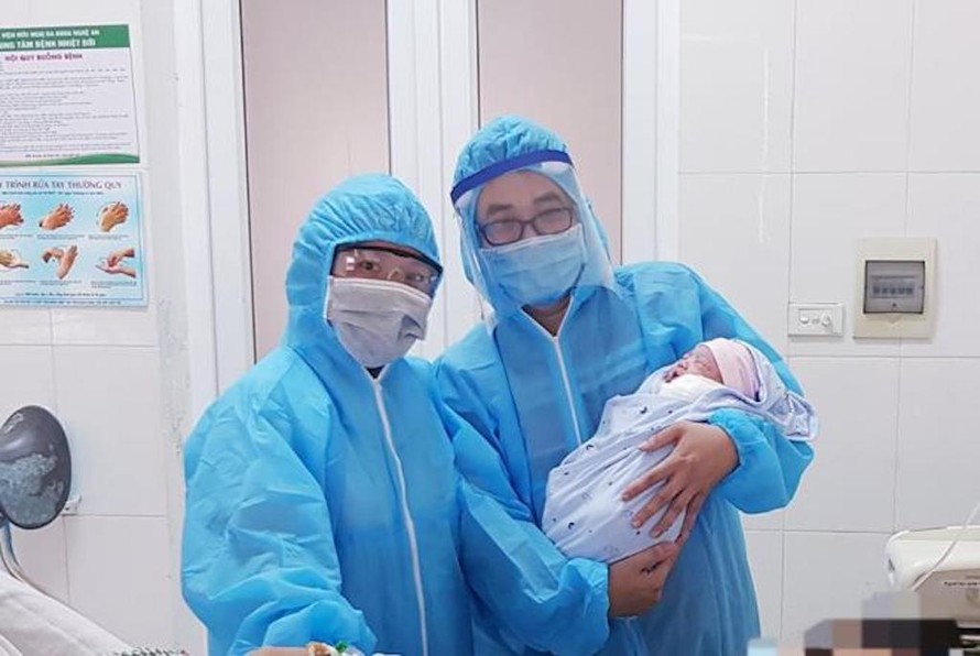 Các bác sĩ chụp ảnh cùng bé gái mới chào đời trong khu cách ly.