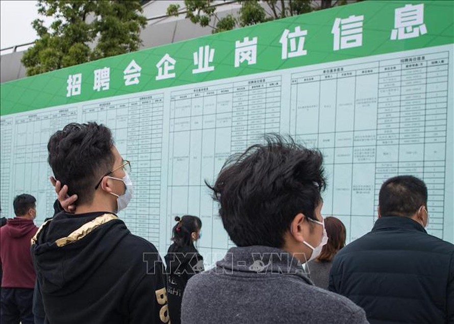 Người tìm việc theo dõi thông tin tại một hội chợ việc làm ở Vũ Hán, tỉnh Hồ Bắc, Trung Quốc. 