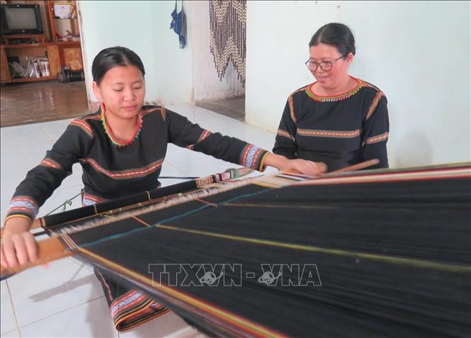 Em Rơ Manh Minh Thư (sinh năm 2006, con gái của nghệ nhân Y Thúy) đang được mẹ truyền dạy nghề dệt thổ cẩm. Ảnh: Dư Toán/TTXVN