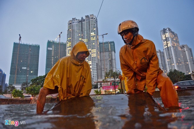 Cơn mưa bắt đầu lúc 16h30 và kết thúc sau đó khoảng 1 giờ nhưng nước đã ngập sâu ở đường Nguyễn Hữu Cảnh. Công nhân cấp thoát nước đô thị phải tích cực dọn cống để chống ngập.
