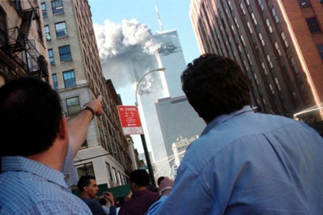 Người đi đường chỉ lên toà Trung tâm Thương mại Thế giới bốc cháy. Ảnh: Reuters