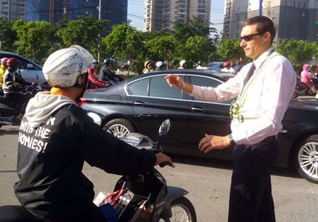 Ông Tây ra hiệu người đi xe máy dừng lại trên Xa lộ Hà Nội để nhường dòng xe đổ vào đường Võ Trường Toản. Ảnh: Sơn Hòa