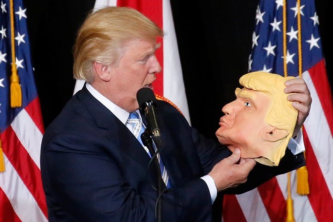 Trump nhìn vào chiếc mặt nạ mô phỏng mình tại buổi vận động tranh cử ở Sarasota, bang Florida hôm 7/11. Ảnh: Reuters