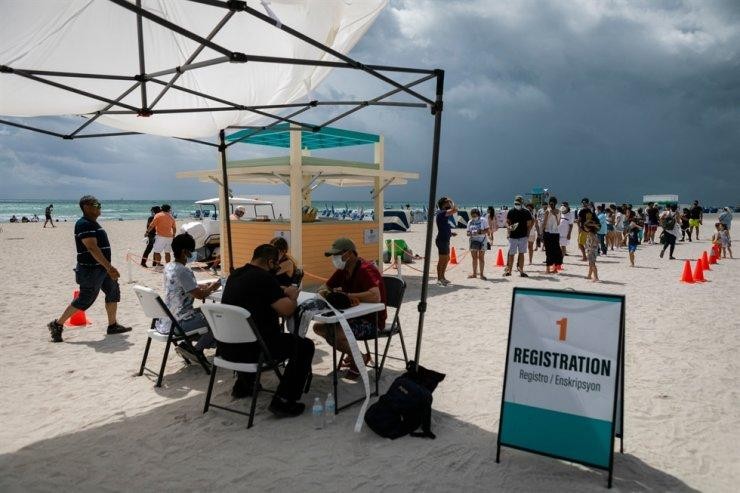 Mọi người đăng ký tiêm chủng vaccine ngừa COVID-19 tại một bãi biển ngày 9/5. (Ảnh: AFP-Yonhap)