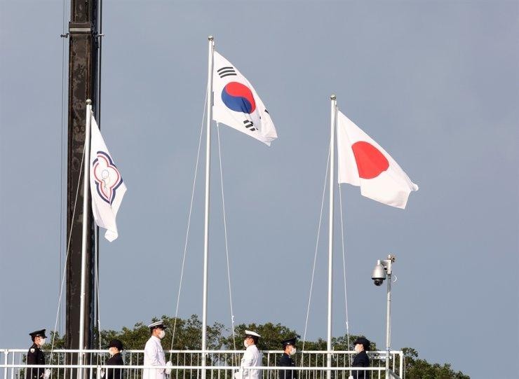 Cờ của 'Đài Bắc Trung Hoa' (Đài Loan), bên trái, tại Lễ trao huy chương cho nội dung bắn cung nam ở Trường bắn cung Công viên Yumenoshima, Tokyo, hôm thứ Hai. Lá cờ có hình một mặt trời nhỏ màu trắng đặt trên một vòng tròn màu xanh lam - một biểu tượng được lấy từ quốc kỳ Đài Loan - và năm vòng tròn Olympic, được bao quanh bởi một bông hoa mận châu Á màu xanh, trên nền trắng. (Ảnh: Yonhap)