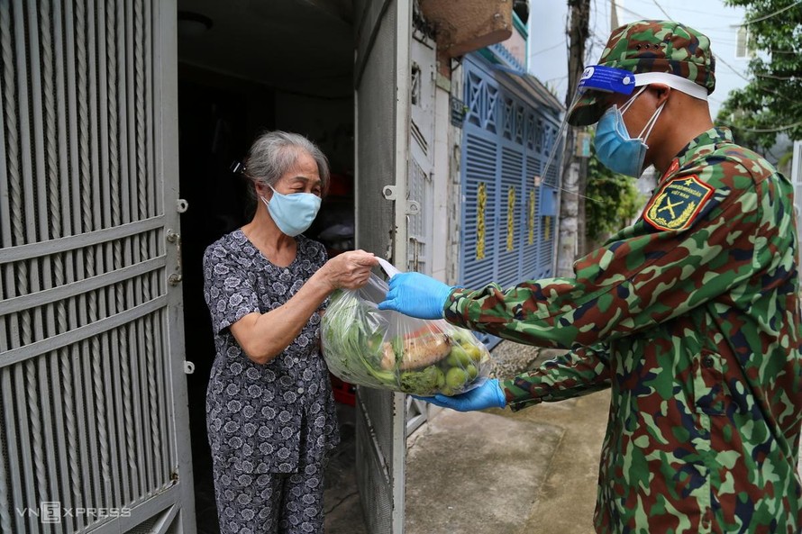 Bà Lê Thị Ánh, 73 tuổi, vui mừng khi nhận túi rau củ đặt mua hộ từ bộ đội. Ảnh: VnExpress.
