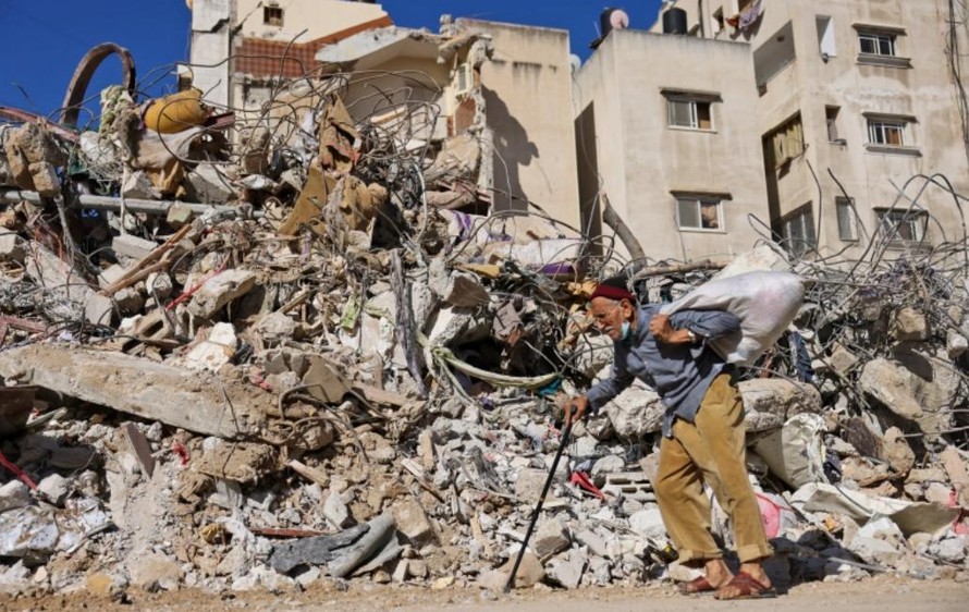 Người đàn ông Palestine đi ngang qua một tòa nhà bị phá hủy bởi cuộc bắn phá của Israel ở Gaza. Ảnh: 