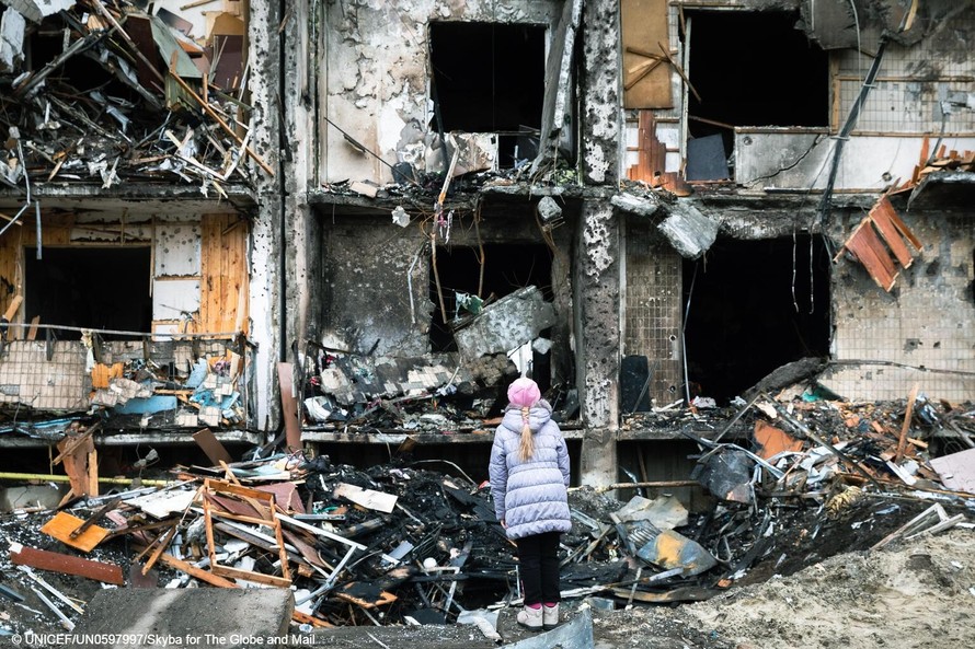 Một đứa trẻ nhìn lên những gì còn lại của một khu chung cư ở Kyiv, Ukraine. Ảnh: UNICEF 