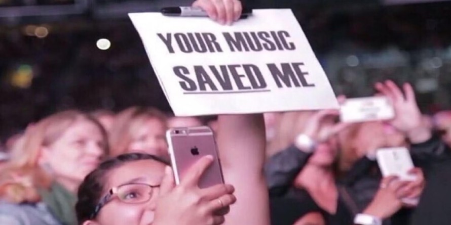 Một người hâm mộ giơ cao tấm biển ghi “Âm nhạc của bạn đã cứu lấy tôi” trong một buổi hòa nhạc.