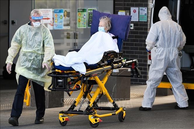 Nhân viên y tế chuyển bệnh nhân nhiễm COVID-19 tới bệnh viện ở Melbourne, Australia. Ảnh: AFP/TTXVN