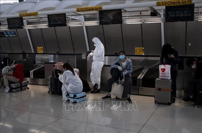Hành khách đeo khẩu trang và mặc đồ bảo hộ phòng lây nhiễm COVID-19 tại sân bay John F. Kennedy ở Queens, New York, Mỹ. Ảnh tư liệu: AFP/TTXVN