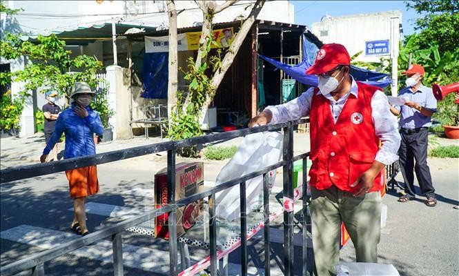 Nhân viên Hội Chữ thập Đỏ thành phố Đà Nẵng đặt "túi hàng gia đình" ở điểm quy định để người dân trong khu phong tỏa đến nhận, đảm bảo công tác phòng, chống dịch. Ảnh minh họa: TTXVN phát